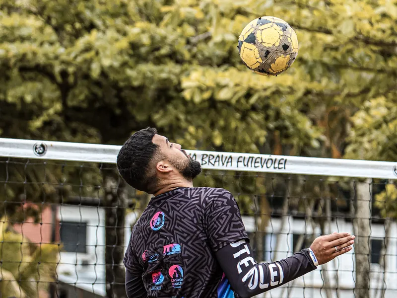 Atleta domina a bola de peito junto à rede do Praia Brava Futevôlei