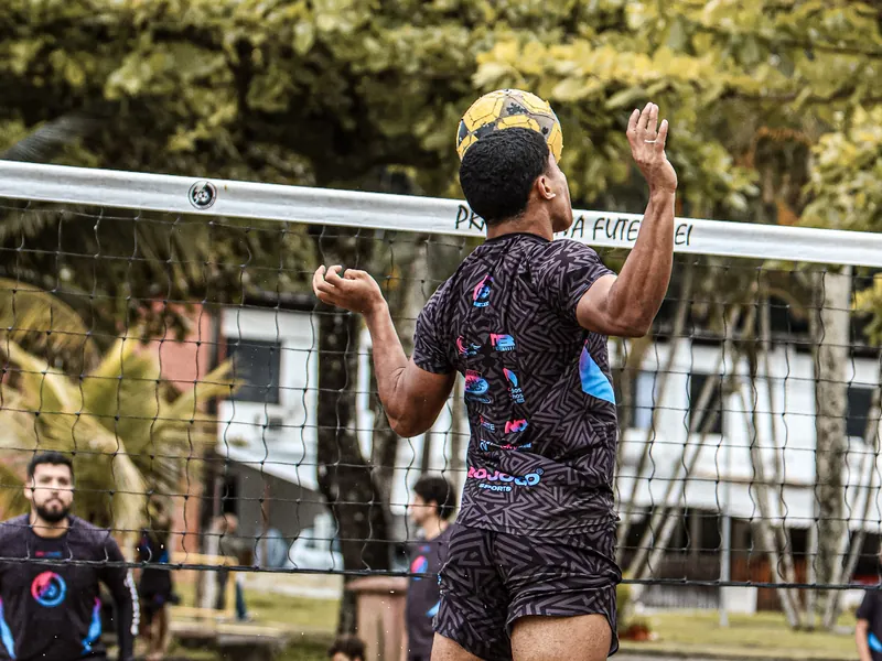Atleta salta para cabecear a bola sobre a rede