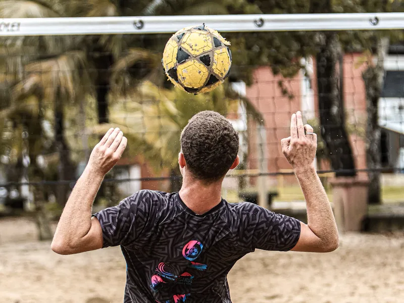 Atleta de costas acompanha a bola no alto